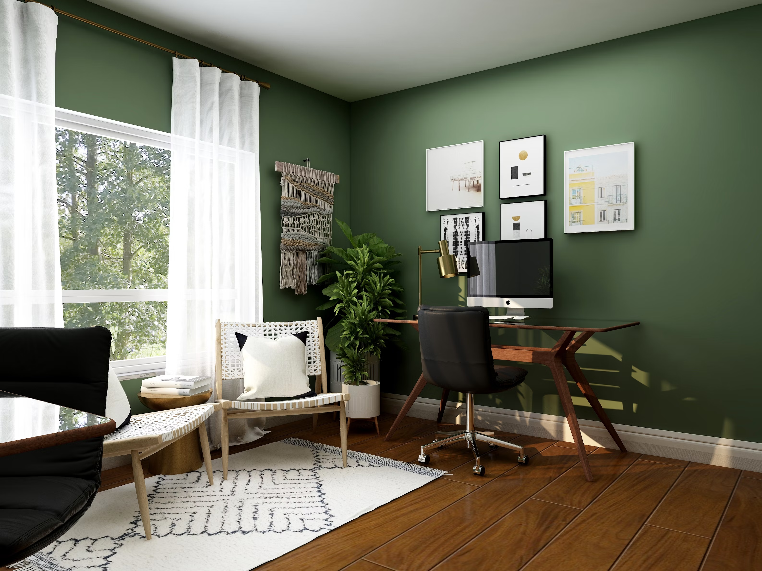 A home office with a green wall, wooden floor, desk with computer, black chair, decorative artwork, plants, two chairs, side tables, and a window with sheer curtains letting in natural light.