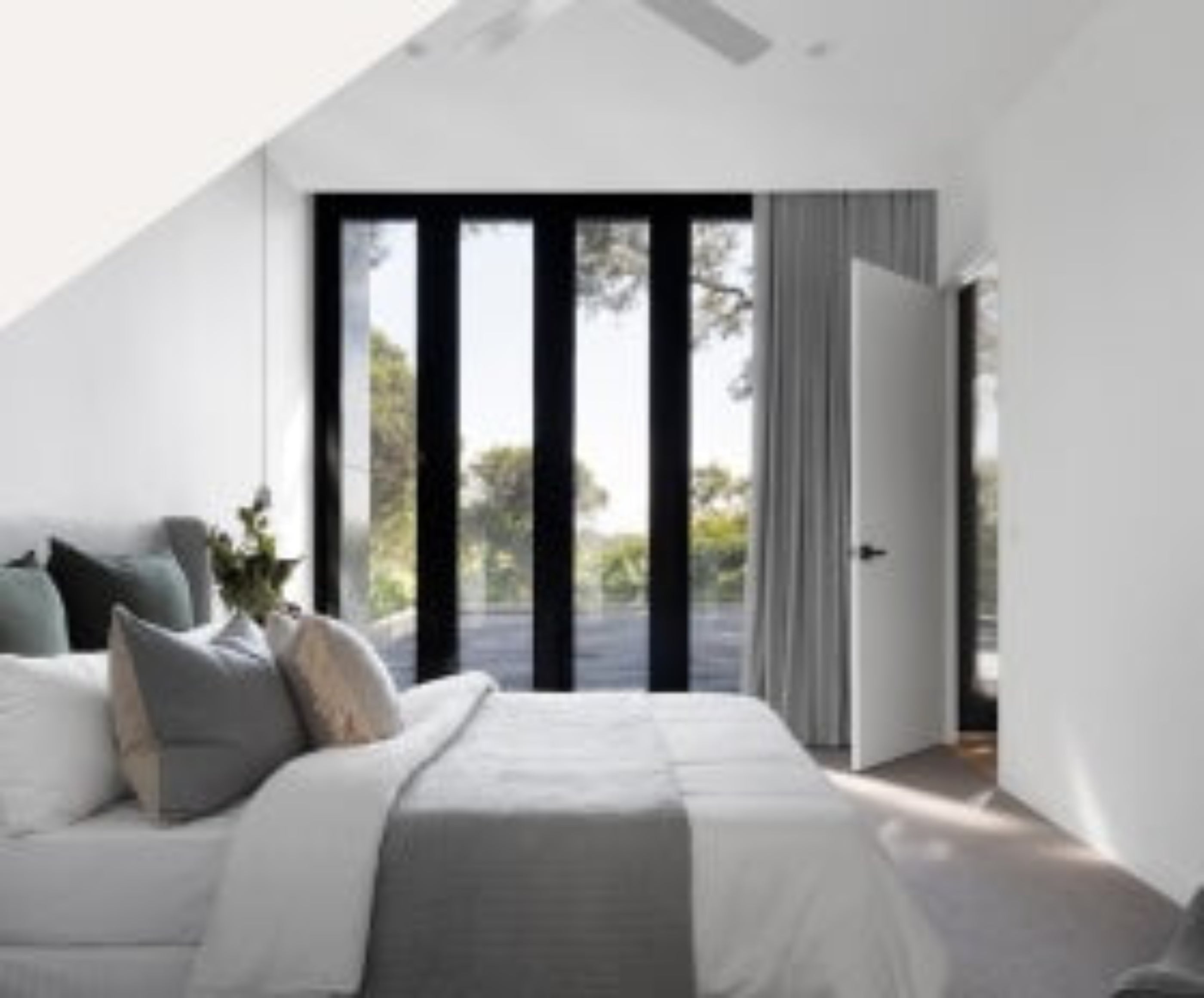 A serene bedroom showcasing a large window and a well-arranged bed, inviting relaxation and comfort.